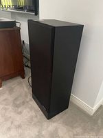 Full view of first speaker showing black cabinet and grille