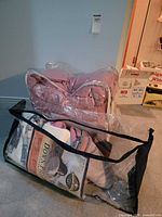 Two clear vinyl bags containing folded pink comforter and accessories
