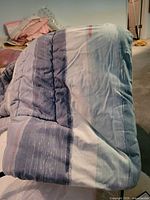 Folded comforter showing blue-teal striped fabric