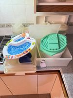 Lot overview of plastic containers, salad spinner, green-lidded bucket and inflatable baby pool seat