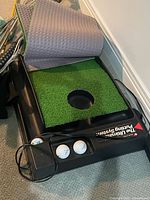Putting mat base showing turf insert and power cord