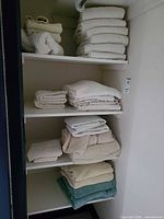 Full view of linen closet shelves showing towels and bedspread