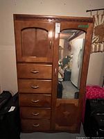 Front view of armoire showing cabinet door, six drawers, mirrored door