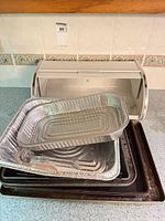 bread box open with stacked foil and metal pans