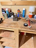 Workbench surface with hand tools, adhesives, lamp, hardware visible