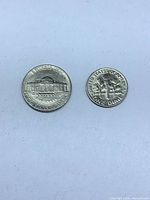 Two U.S. 10-cent coins reverse sides visible, one showing Monticello‐style building design, other showing torch design