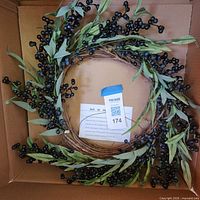Full view of wreath inside box showing grapevine base, leaves and berries