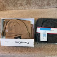 Boxed Calvin Klein tan hat beside packaged Club Room gray scarf