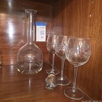 decanter and three matching etched floral wine glasses displayed on wooden shelf