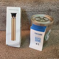 Boxed gold hair clipper beside Epilady tin
