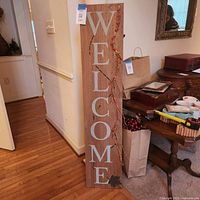 Front view of vertical welcome sign showing lettering and berry vine