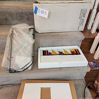 Panel, mounting frame, original box and foam packaging laid out on steps
