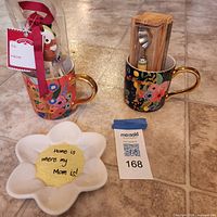 Group shot of both floral mugs, trinket dish, boxed coffee spoon, wrapped measuring spoon set