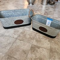 Pair of galvanized metal planters on floor