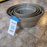 All four nested sage green stoneware bowls showing exterior color and embossed fruit motif