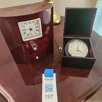 Mantel clock and travel clock box displayed side by side