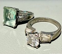 Two sterling silver rings, square green stone ring and round clear stone ring
