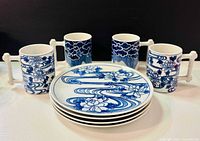 Group shot of four mugs and four plates showing patterns and handles