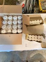 Open boxes showing tall votive candles in plastic cups and loose tea lights