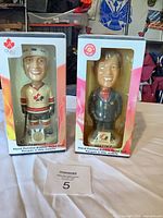 Both boxed bobbleheads side by side on table