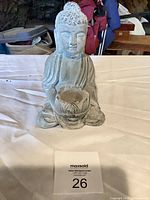 Front view of gray concrete Buddha statue holding lotus candle cup