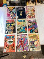 Nine bagged & boarded comics laid out 3×3 on table