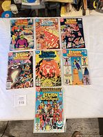 Seven bagged Legion of Super-Heroes comics laid out