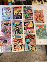 12 bagged DC comics laid out in grid