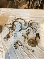 Overview of mixed jewelry lot on table including necklaces, earrings, belt buckle, bracelet