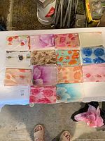 Overhead view of 13 packaged scarves arranged on table