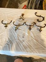 All six brass hooks arranged on table showing variety and condition