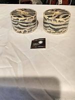 Both zebra print pillar candles side by side on table with Swazi Candles tag