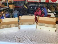 Three long white card boxes on table, lids open showing rows of cards