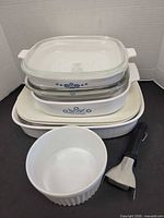 Stacked view of all cookware pieces showing casseroles with lids, baker, bowl and handle