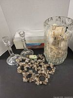 Overview of lot showing candlesticks, boxed centerpiece vase, ribbed vase with fillers, napkin rings