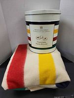 Blanket folded with popcorn tin on top showing size relation and stripe design