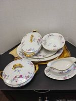 Stack of Limoges serveware showing lidded casseroles, open bowls, gravy boat and platters