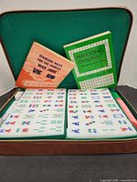 Open case showing two trays of Mahjong tiles and three manuals