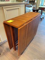 Table folded showing compact profile and teak finish