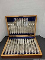 Open wooden box showing all 18 EP flatware pieces arranged in fitted royal-blue velvet interior