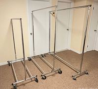 Three chrome rolling garment racks side by side