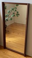 Full view of mirror leaning against wall