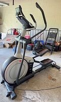 Side view of NordicTrack E 9.5i elliptical showing frame, pedals and flywheel