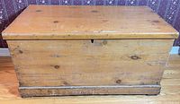 Front view of solid pine blanket box showing wood grain, lid, keyhole and base trim