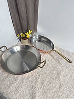 Two copper pans on surface, showing size difference