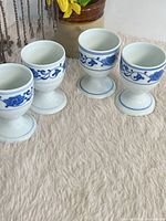 Four matching flow blue porcelain egg cups displayed on fuzzy surface