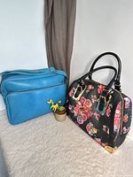 Black floral satchel and blue shoulder bag side by side