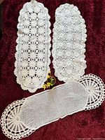 Overview of the three white crochet lace runners on red background