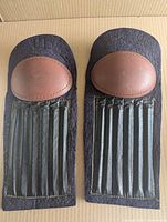 Front view of both shin pads showing leather caps, felt bodies and oak slats