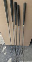Five irons standing upright showing full length, grips to heads